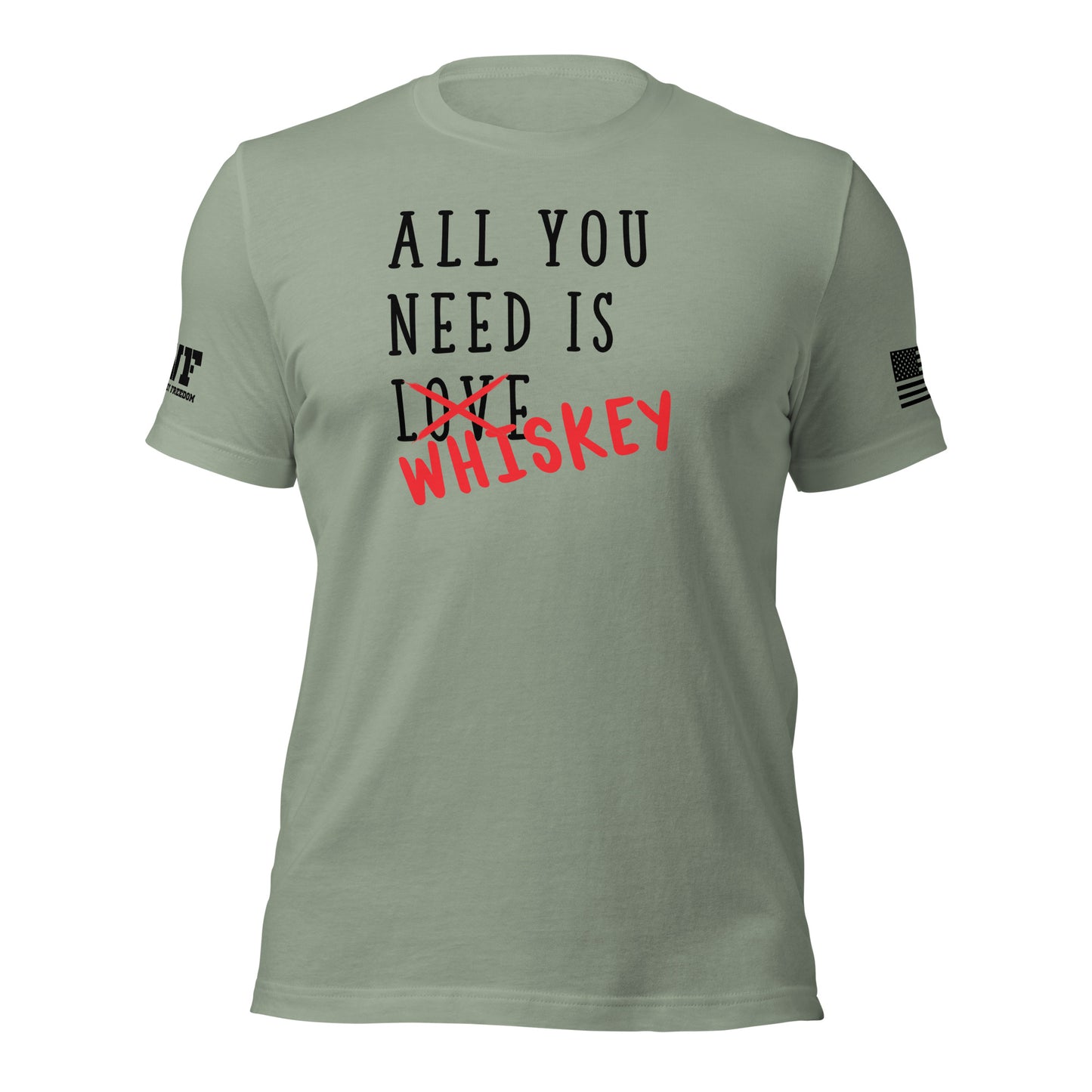 Rugged sage green t-shirt featuring bold, distressed text that says "All You Need Is Love" — the word "Love" is crossed out with a rough red strike-through, and the word "whiskey" is scrawled over it in a bold, handwritten style. The design blends humor and grit with a rebellious, rugged vibe.